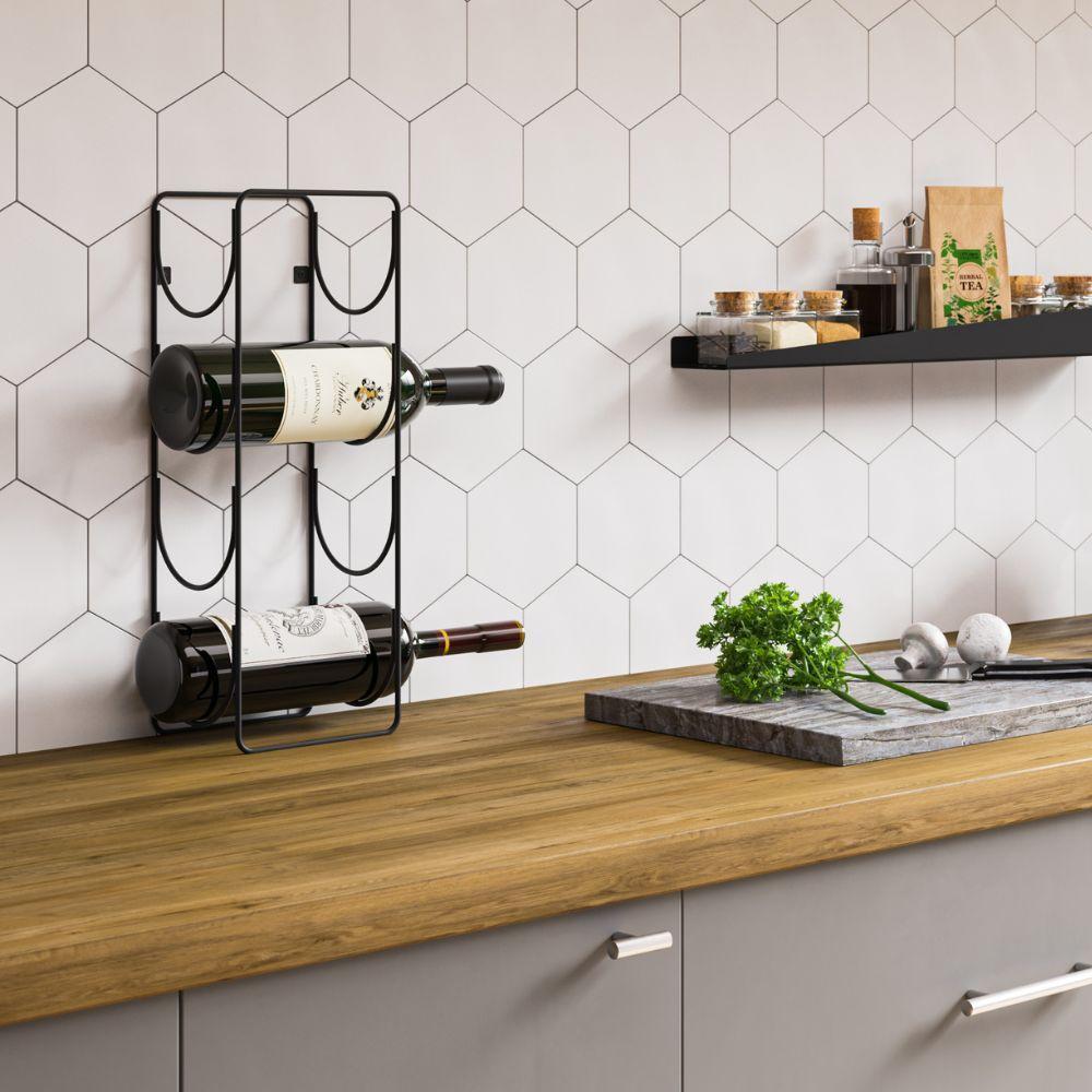 Μία μαύρη μεταλλική βάση με δύο μπουκάλια κρασιού, στερεωμένη επάνω από πάγκο κουζίνας με λευκά πλακάκια